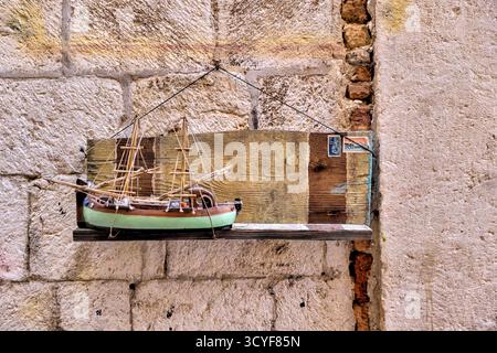Handgefertigte Modellboote, die an den Mauern der Steingasse in der Altstadt von Dubrovnik in Kroatien ausgestellt werden, verbinden maritimen Charme mit historischer Architektur. Stockfoto