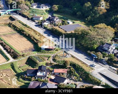 Eine ländliche Gegend mit einer Schotterstraße und ein paar Häusern. Die Häuser sind klein und es gibt keine Autos auf der Straße Stockfoto