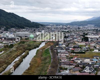 Eine Stadt mit einem Fluss, der durchfließt und einem großen grünen Ball in der Mitte. Die Stadt ist voll von Häusern und Gebäuden, und der Fluss ist umgeben von Stockfoto