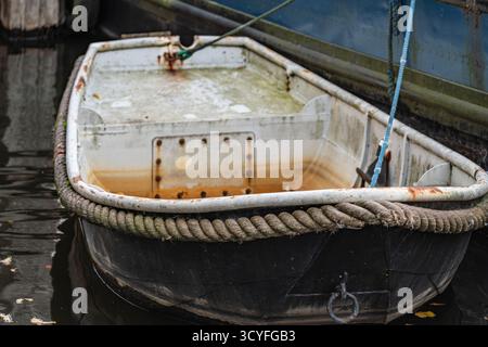 Altes kleines weißes Boot mit dicken Seilen am Pier befestigt – Nahaufnahme von vorne Stockfoto