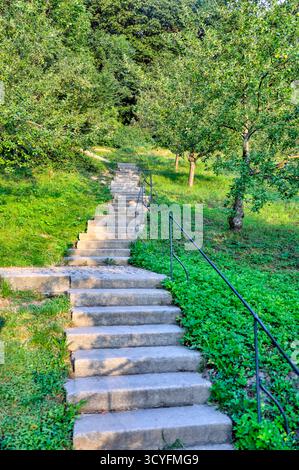 Steintreppen führen durch Grün- und Obstbäume auf dem Petrinberg in Prag, Tschechische Republik. Stockfoto