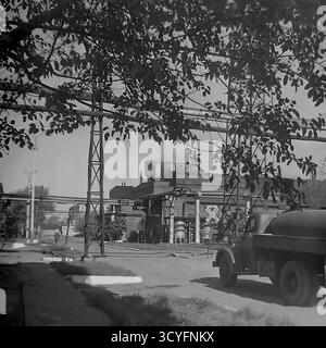Dieses Archivfoto aus den 1970er Jahren zeigt das Gebiet der Slawjansk Armature and Insulator Factory (AIF) in Slowiansk, Ukrainische SSR. Der Schuss erfasst eine interne Fabrikstraße. Im Vordergrund steht ein Tankwagen, wahrscheinlich ein ZIS-Modell. Im Hintergrund befinden sich eine große Produktionswerkstatt, zahlreiche erhöhte Rohrleitungen auf Metallstützen und Rauchschornsteine. Das Bild fängt die Arbeitsatmosphäre eines sowjetischen Industrieriesen ein, ein wichtiger Teil des friedlichen Donbass. Stockfoto