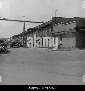 Dieses Archivfoto aus den 1970er Jahren zeigt einen Versorgungsbereich in der Slawjansk Armature and Insulator Factory (AIF) in Slowiansk, ukrainische SSR. Ein Schwerlastwagen, möglicherweise ein KrAZ, steht auf einem Feldweg neben Materialvorräten. Eine lange Ziegelwerkstatt und eine erhöhte Pipeline sind sichtbar. Das Bild fängt die schlichte Industrielandschaft und die tägliche Logistik eines großen sowjetischen Werks ein, ein Dokument der friedlichen Donbass-Ära Stockfoto