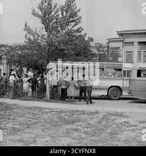 Dieses Archivfoto aus den 1970er Jahren zeigt eine Sommerszene in Sloviansk, UdSSR. Eine Gruppe von Menschen, Männer und Frauen in leichter Kleidung, versammelt sich an einem Straßenrand. Sie warten darauf, an Bord eines alten sowjetischen Intercity-Busses zu gehen, wahrscheinlich ein LAZ-697-Modell für einen kollektiven Ausflug. Dieses Bild zeigt einen typischen Aspekt des gesellschaftlichen Lebens in der Sowjetzeit, wie etwa eine werkseitig organisierte Freizeitreise für Arbeiter Stockfoto