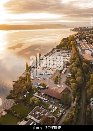 Ein Hafen mit verankerten Booten bei Sonnenuntergang, umgeben von einer urbanen Landschaft im Herbst, Ueberlingen, Bodensee, Deutschland Stockfoto