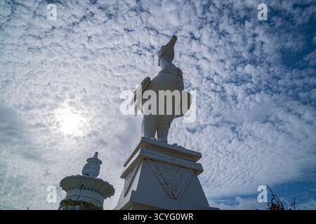 Phuket Thailand. 13. August 2025: Eine markante weiße Skulptur steht hoch unter einem strukturierten, bewölkten Himmel, deren anmutige Form sich mit dem flauschigen c kontrastiert Stockfoto