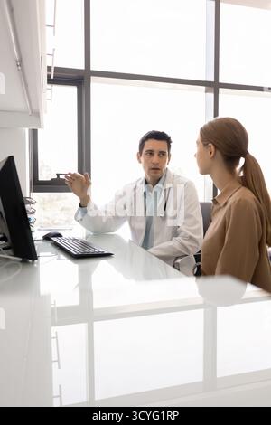 Junger Hausarzt-Leitgespräch mit weiblicher Patientin in der Klinik Stockfoto