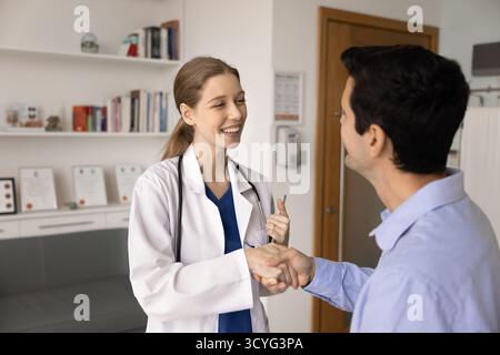 Hausarzt in Uniform gekleidet mit Handschütteln bei männlichem Patienten Stockfoto