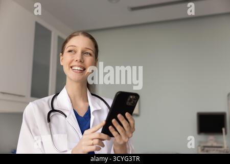 Junge lächelnde Krankenschwester oder Hausärztin in Uniform mit Smartphone Stockfoto