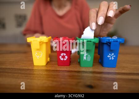 Junge Frau, die ein Stück Papier in den roten Mülleimer wirft Stockfoto