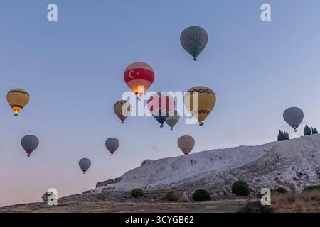 Ein Dutzend bunter Heißluftballons fliegen bei Sonnenaufgang, Pamukkale, Türkiye Stockfoto