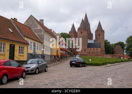 Ein malerischer Blick auf Kalundborg, Dänemark, mit farbenfrohen traditionellen Häusern entlang einer kopfsteingepflasterten Straße und der berühmten fünftürmigen Kalundborg Kirche i Stockfoto