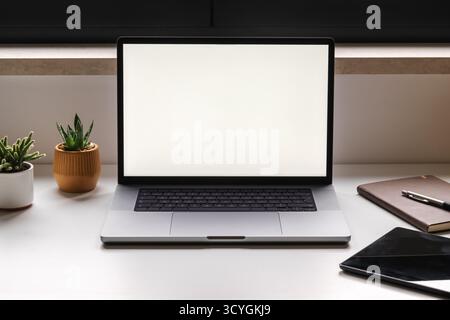 Minimaler kreativer Schreibtisch mit Notebook-Mockup, Notebook, Tablet und grünen Pflanzen, Symbol für digitale Produktivität und Balance. Selektiver Fokus. Stockfoto