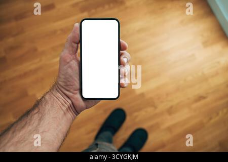 Smartphone mit leerem Bildschirm in gemütlichem Wohnzimmer, das digitale Verbindung, Kommunikation und modernen Lebensstil symbolisiert. Selektiver lichtwellenleiter Stockfoto