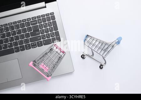 Online-Shopping. Laptop mit Supermarktwagen auf weißem Hintergrund. Draufsicht. Flache Lagen Stockfoto