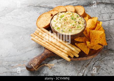 Deviled Egg Dip Vorspeise für ein Buffet oder Picknick mit Nachos, Brotstangen und Toast in Nahaufnahme auf einem Holzbrett auf dem Tisch. Horizontal Stockfoto