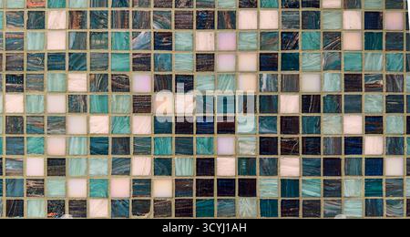 Dekorative Wand aus Glasmosaikfliesen in Blau-, Petrol- und Weißtönen mit reflektierender Textur. Stockfoto
