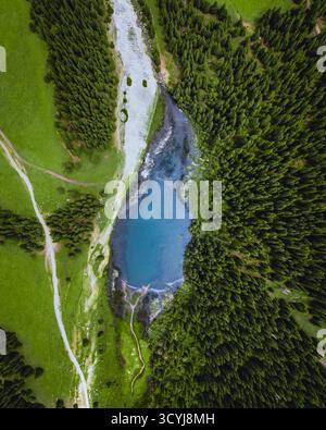 Atemberaubende vertikale Aussicht auf einen türkisfarbenen Bergsee, umgeben von einem dichten, dunkelgrünen Nadelwald Stockfoto