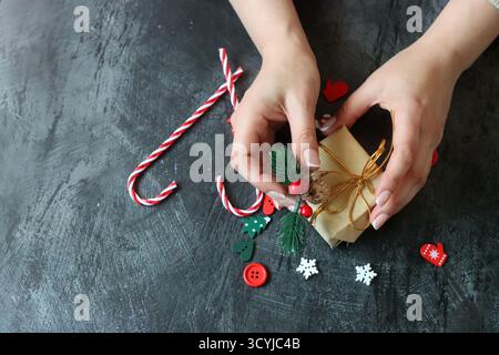 Weibliche Hände, die Weihnachtsgeschenkkasten auf dunklem Hintergrund halten, Nahaufnahme Stockfoto