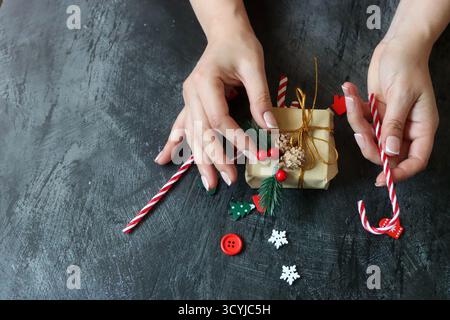 Weibliche Hände, die Weihnachtsgeschenkkasten auf dunklem Hintergrund halten, Nahaufnahme Stockfoto