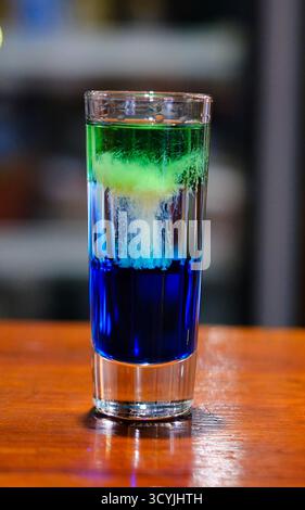 Array Shot Gläser mit lebendigen und farbenfrohen Getränken stehen auf einer eleganten Bartheke. Verschiedene Farbtöne reflektieren das Licht und schaffen eine energiegeladene Atmosphäre, perfekt für einen Abend. Stockfoto
