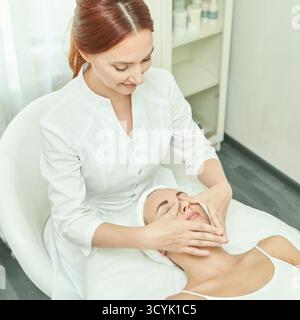 Weibliche kaukasische Erwachsene, die Gesichtsbehandlung von weiblichen kaukasischen Erwachsenen Hautpflegespezialisten im Spa-Setting erhalten. Stockfoto