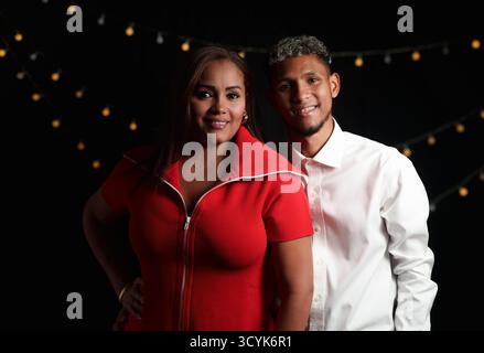 Eine Frau in rot gekleidet und ihr Sohn in weiß posierten für ein Foto mit schwarzem Hintergrund Stockfoto