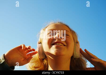 Fröhliches Kind hört Musik mit Kopfhörern im Freien Stockfoto