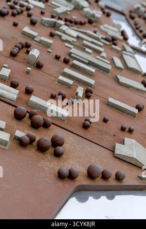 Hochwinkelaufnahme mit flachem Fokus eines braunen Miniaturmodells einer Stadt mit grauen rechteckigen Gebäuden und kleinen, runden Bäumen. Stockfoto