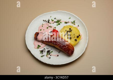 Ein Gourmet-Teller mit verführerischer Wurst und lebendigen Beilagen, kunstvoll präsentiert, um zu erfreuen Stockfoto