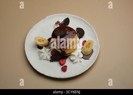 Genießen Sie köstliche Pfannkuchen mit reichhaltiger Schokoladensauce und frischem Obst zum Frühstück Stockfoto