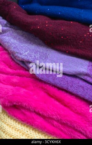Ein Stapel gestrickter Pullover. Verschiedene Strickmuster. Warme handgemachte Kleidung. Strickpullover-Cardigans. Produktkonzept erstellen. Wintermode. Stockfoto