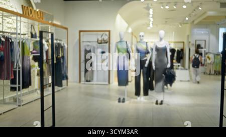 Verschwommenes Interieur im Einzelhandel mit weichem Bokeh und defokussierten Schaufensterpuppen und Bekleidungsregalen; Hintergrundhinterlage im Copyspace ruhig. Stockfoto