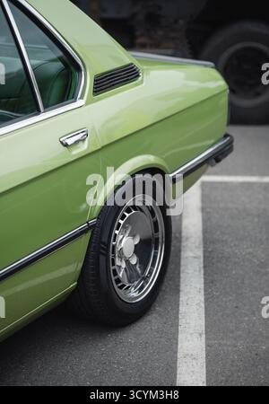 Hinterer Teil des alten grünen Autos auf dem Parkplatz. Hintertür, Rad und Seitenblech einer 1970er-Limousine auf einer Straße Stockfoto