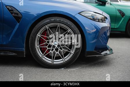 Nahaufnahme der Seitenansicht des vorderen Teils des blauen BMW. Vorderrad, Kotflügel, Stoßfänger und Scheinwerfer des BMW M4. Stockfoto