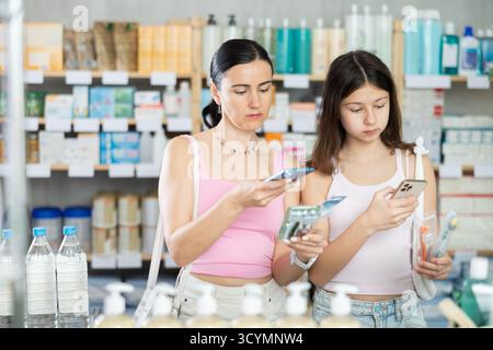 Positiv glückliche Mutter- und Töchterkäufer in der Apotheke halten und die beste Zahnbürste wählen, QR-Code scannen Stockfoto