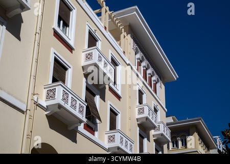 Einzigartige Architektur mit einer hellgelben Fassade mit kunstvoll gemusterten weißen Balkonen und dunkelbraunen Fensterläden vor einem tiefblauen Himmel Stockfoto