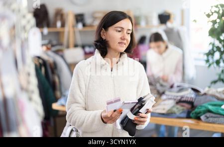 Frau schaut sich Produkte im Geschäft an und wählt Socken aus. Einkaufen für die ganze Familie Stockfoto
