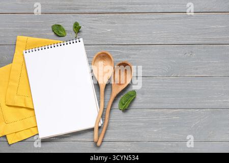 Leeres Rezeptbuch mit Löffeln und Minze auf dunklem hölzernem Hintergrund Stockfoto