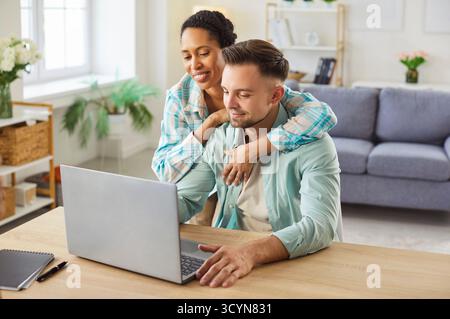 Glückliches Paar, das Finanzen überprüft oder zusammen online einkaufen kann Stockfoto