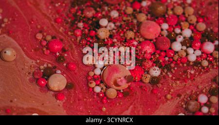 Farbblasen. Ölflüssigkeit. Defokussierte rote rosa orange weiße Tinte Glitzer Acryl Wasser glänzende runde Textur schwimmend auf abstraktem Kunsthintergrund. Stockfoto