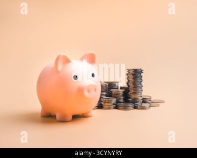 Rosafarbene Schweinebank mit gestapelten Münzen auf weichem pastellfarbenen Hintergrund, repräsentiert Spargeld, Finanzplanung, Altersvorsorge, Gewinn, persönlicher Finan Stockfoto