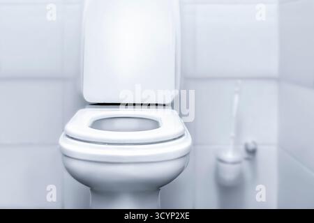 Diese minimalistische Toilette verfügt über ein elegantes, weißes Design, das sich an einer hellen Wand befindet. Das Zimmer betont eine saubere und einfache Ästhetik, perfekt für Stockfoto