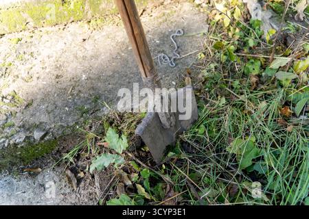 Schaufel, die neben einem Betonweg oder einer Betonmauer im Boden festsitzt, Stockfoto