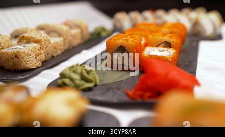 Sushi-Brötchen werden auf schwarzen Tellern des Restaurants serviert Stockfoto