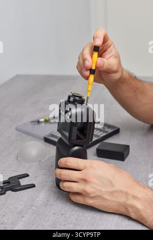 Ein professioneller Techniker repariert einen Kamerablitz. Service für Fotoausrüstung. Repariert Fotoblitz, Speedlight Stockfoto