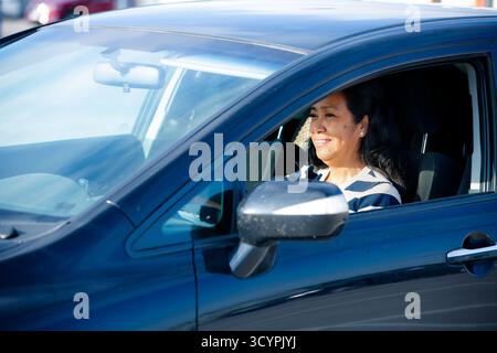 Frau im mittleren Alter, die in Farbe Auto fährt, mit Fokus auf Geschäft, Mobilität und Vielfalt in der modernen vernetzten Gesellschaft von heute. Stockfoto