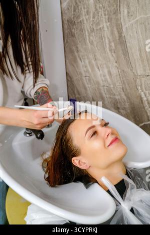 Eine Nahaufnahme der Hand eines Friseurs und eines zufriedenen Kunden, der ein Peeling anwendet Stockfoto