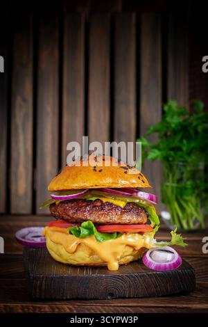 Rindfleisch-Hamburger. Sandwich mit Rindfleisch-Burger, Tomaten, Käse, eingelegter Gurke und roten Zwiebeln. Cheeseburger Stockfoto