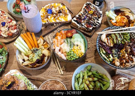 Gesunder Brunch-Tisch mit farbenfrohen, frischen Poke-Schüsseln und Avocadotoasts Stockfoto